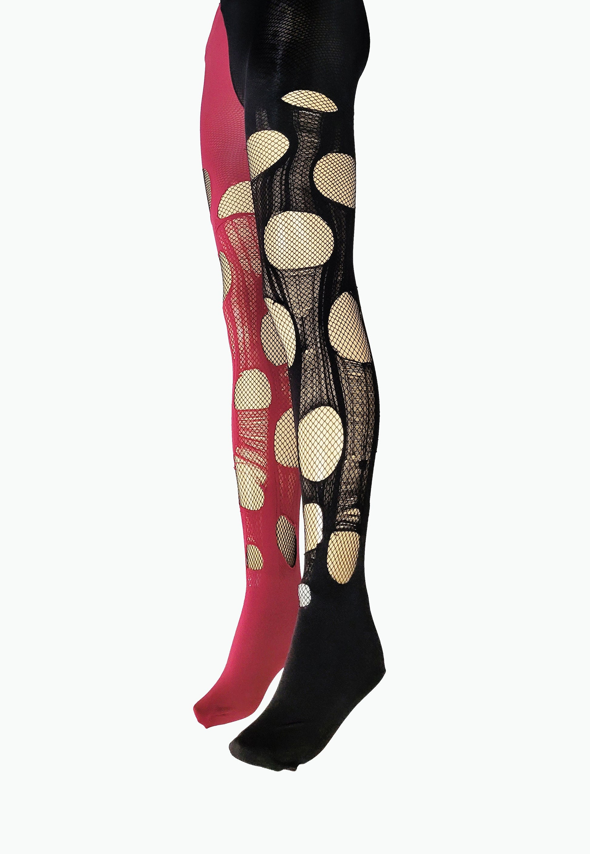 May include: A pair of footed tights featuring a split-color design with one leg in solid magenta and the other in solid black. Both legs are decorated with large, circular cutouts that reveal a fine, integrated black fishnet mesh fabric.